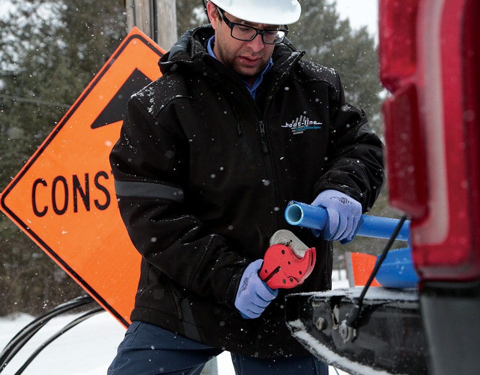 Contractor holding a water line freeze protection system and cutting pliers on tailgate at job site