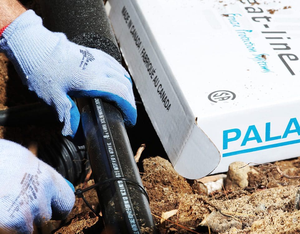 Contractor installing external self-regulating heat trace system to pipe outdoors