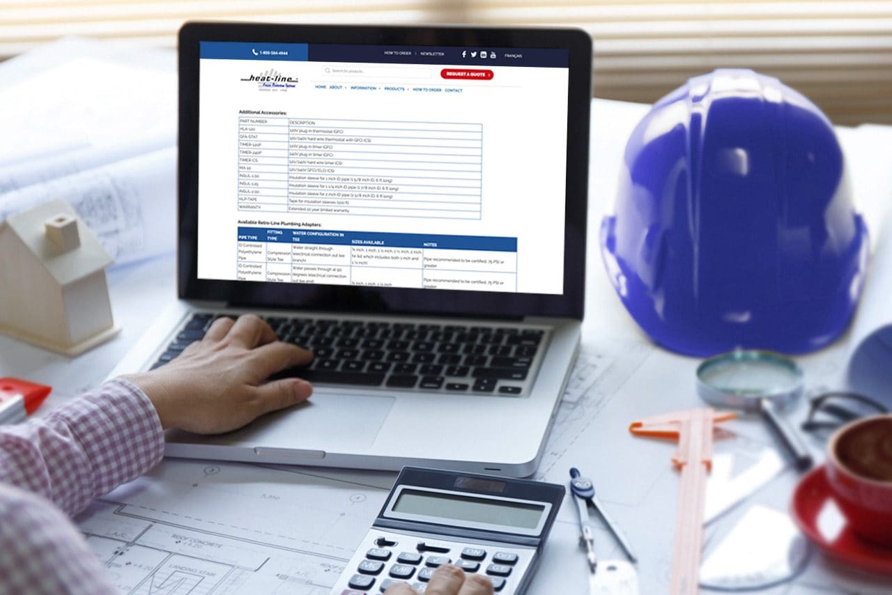 Hand on keyboard of laptop, other hand on calculator, Heat-Line website on screen of laptop